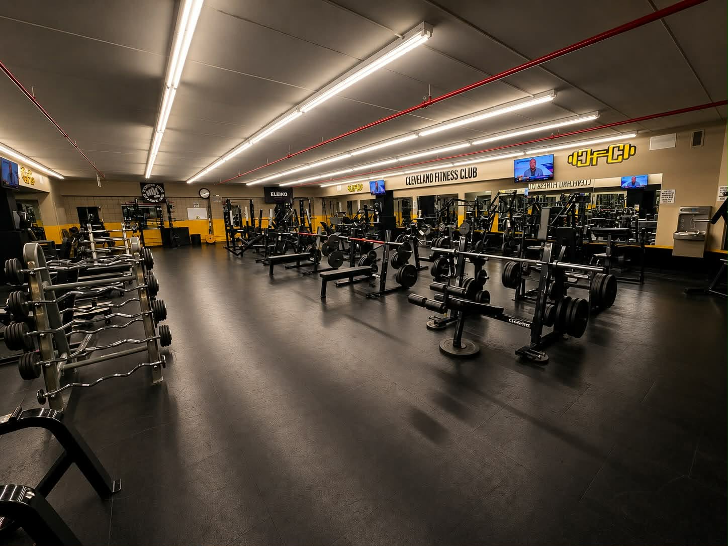 Free weight room with dumbbells, barbells, and benches for strength training at Cleveland Fitness Club